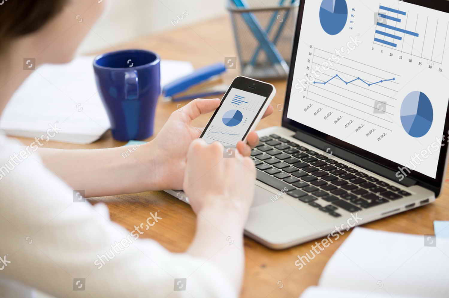 stock-photo-close-up-rear-view-of-young-business-woman-working-in-office-interior-on-pc-holding-smartphone-and-472132963